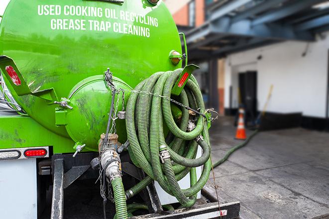 a professional plumber using a pump to empty a grease trap in Chenango Forks